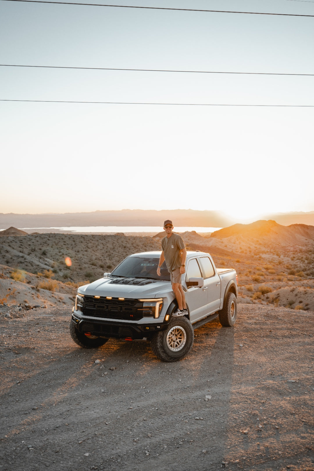 Nate standing on his Ford Raptor at sunset in the Utah desert